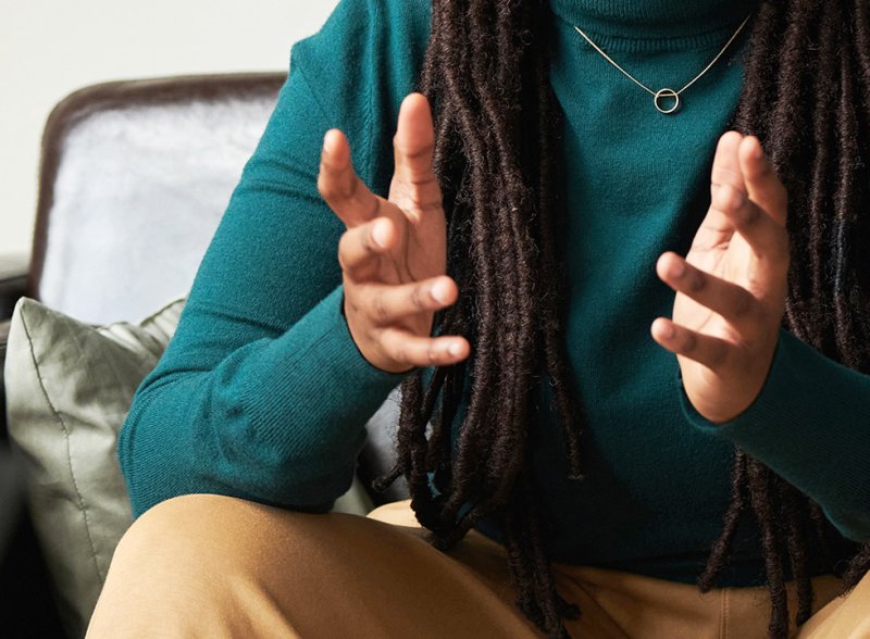 A person with dreadlocks talking with their hands