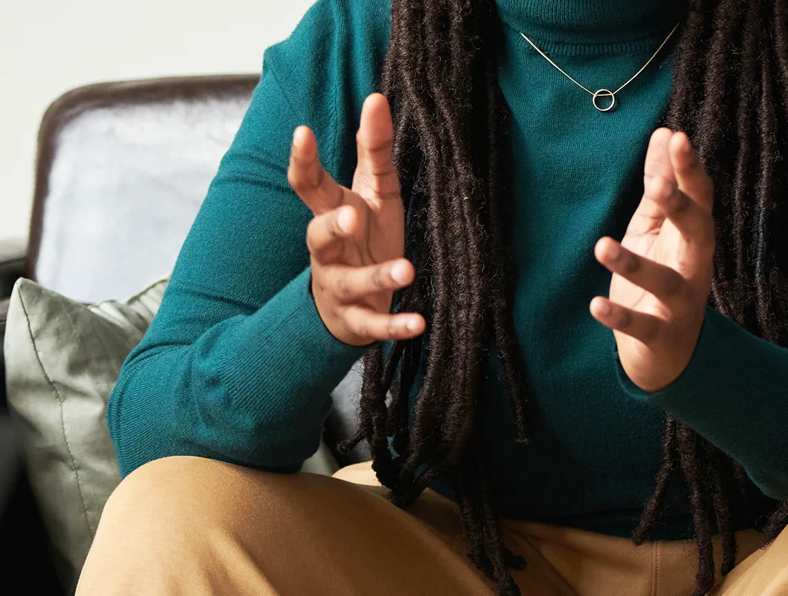 A person with dreadlocks talking with their hands